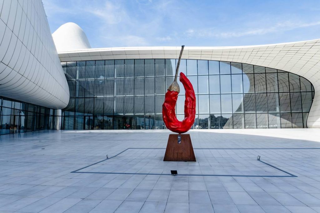 Red chili pepper sculpture in front of modern building