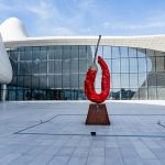 Red chili pepper sculpture in front of modern building