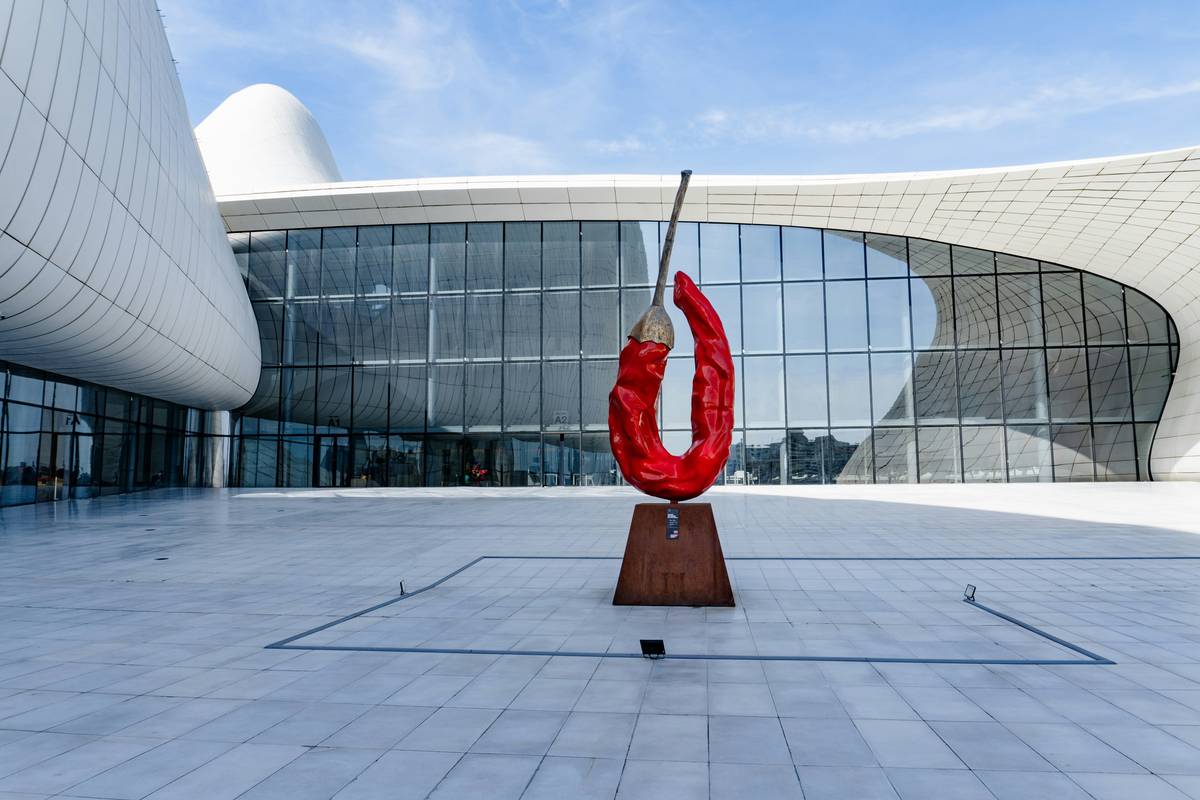 Red chili pepper sculpture in front of modern building